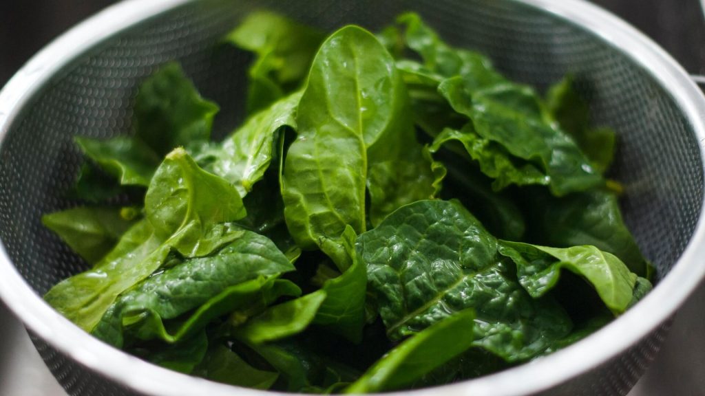 Bowl of raw spinach leaves.